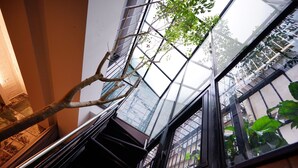 Un interior moderno con techo de vidrio, una escalera y vistas al exterior.