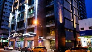 Edificio de un hotel de varios pisos con señalización iluminada, incluyendo 