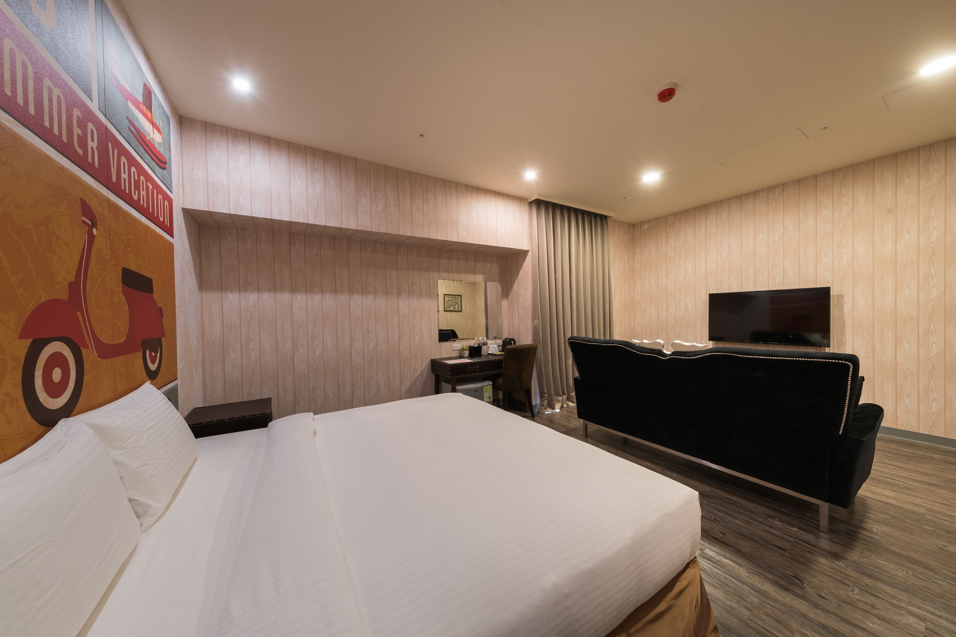 Habitación de hotel con una cama grande, un escritorio con silla, televisión y una pared con un mural.