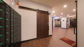 A hotel lobby with a sliding door, a row of lockers, and a reception desk.