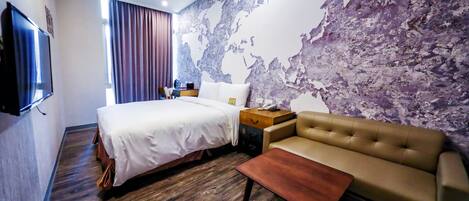 Una habitación de hotel con una cama grande, un sofá, suelo de madera, un mural de un mapa mundial y un televisor de pantalla plana.