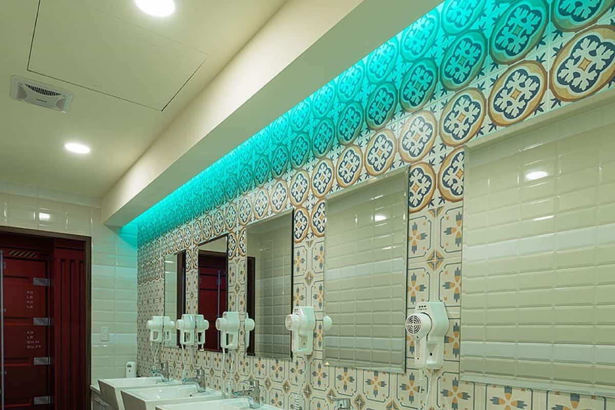 Un baño largo y estrecho con varios lavamanos y espejos.
