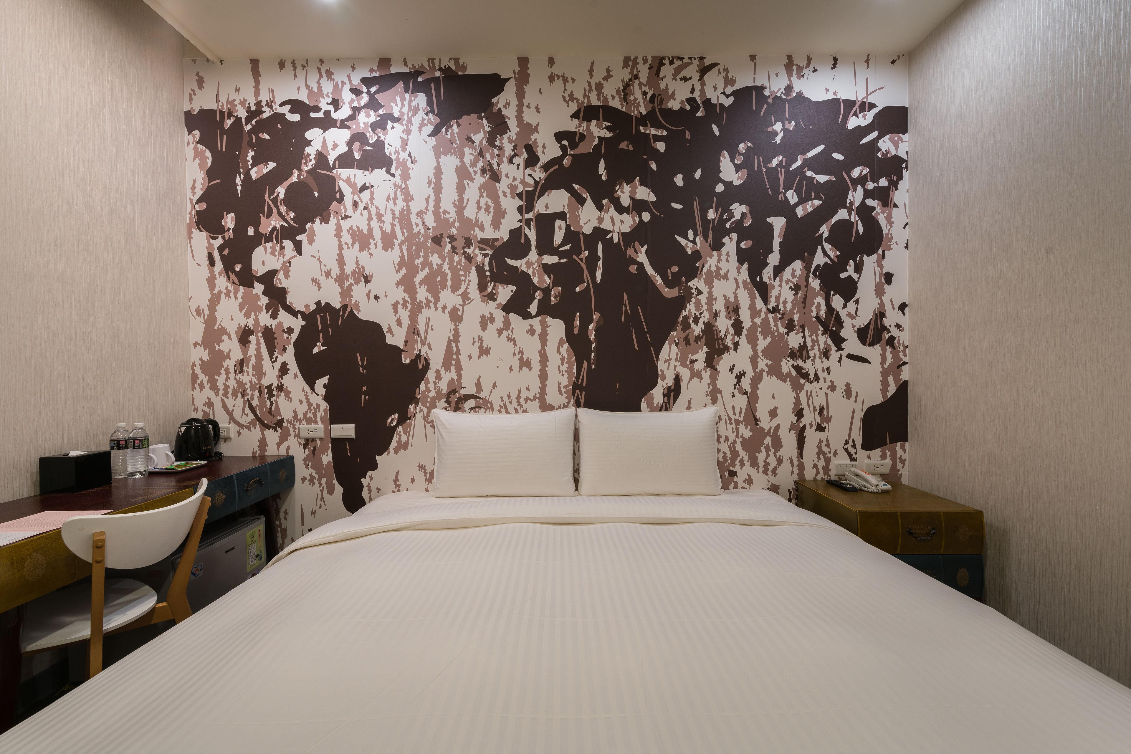 A hotel room with a bed, a desk, a chair, and a nightstand.
