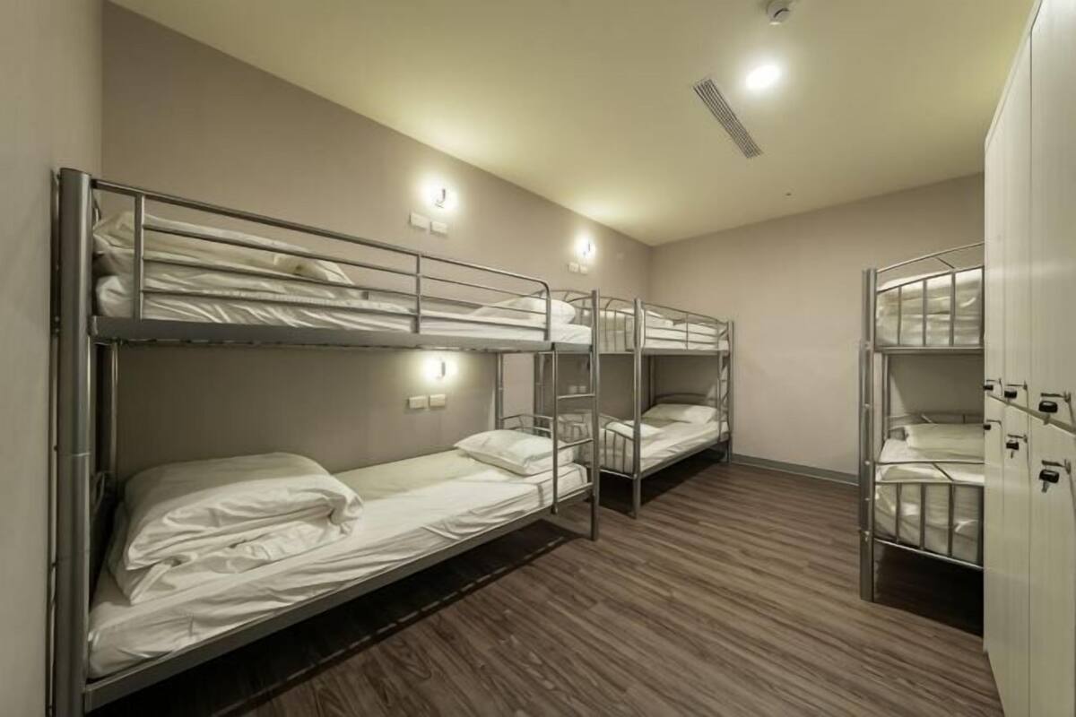 Una habitación con literas, suelo de madera e iluminación en la pared.
