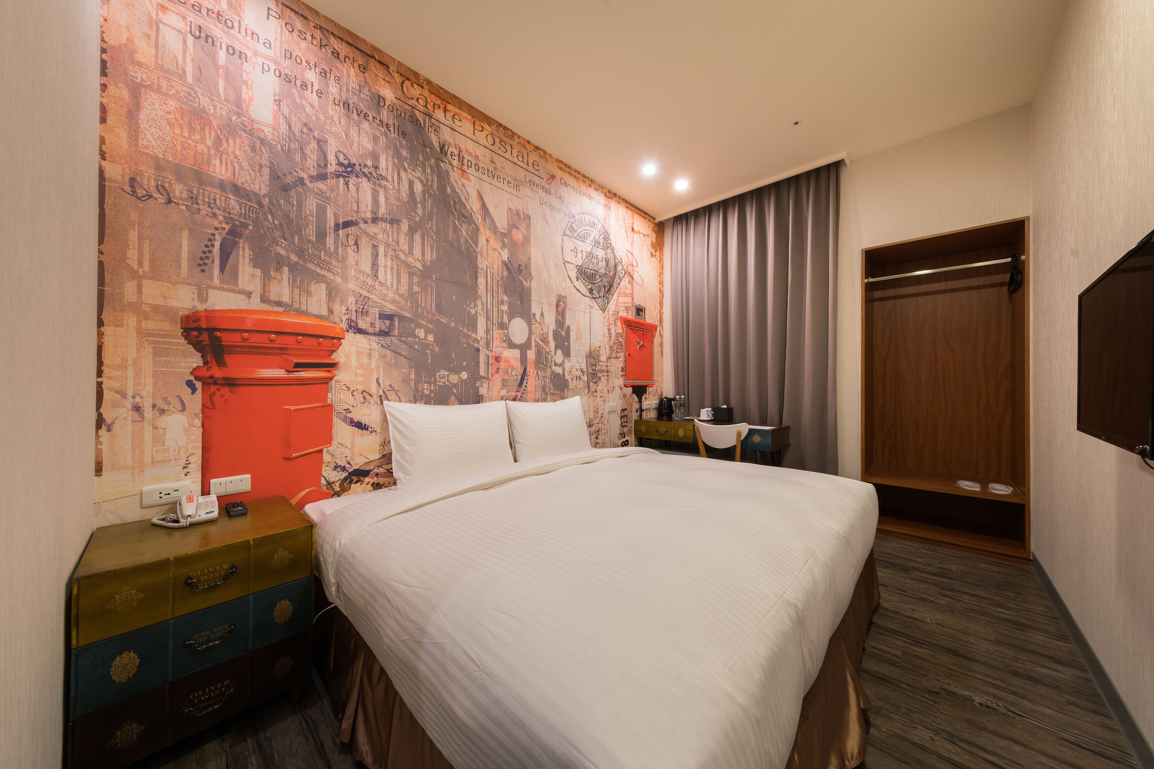 Une chambre d’hôtel avec un grand lit, une armoire en bois, un bureau avec une lampe et un mur décoré d’une carte ancienne.