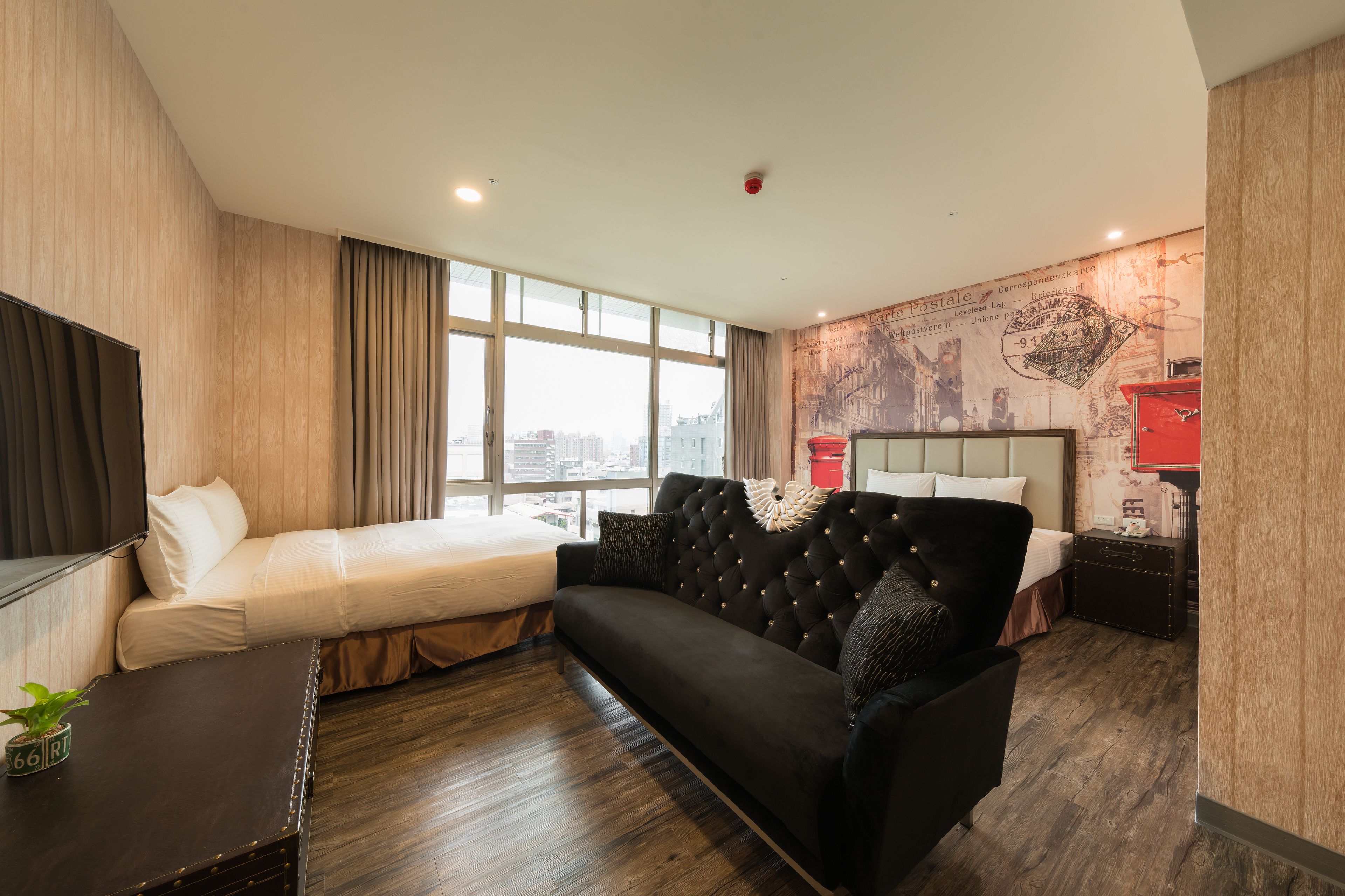 Una habitación de hotel moderna con una cama grande, un sofá, un televisor y vistas a la ciudad.