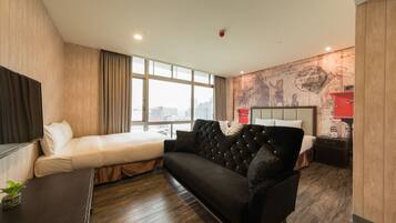 Una habitación de hotel moderna con una cama grande, un sofá, un televisor y vistas a la ciudad.