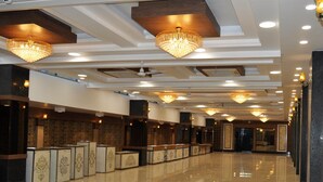 A hotel lobby with multiple reception counters, chandeliers, and a polished floor.