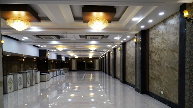 A long, well-lit corridor with reflective flooring, decorative ceiling lights, and patterned wall panels.