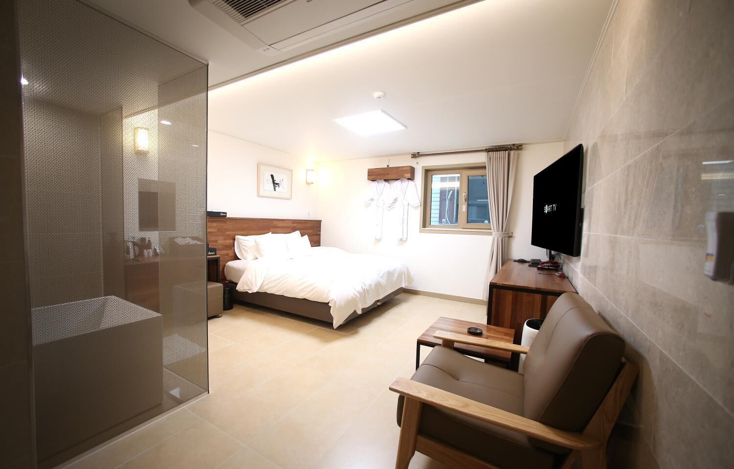 Habitación de hotel con cama, televisión, escritorio y zona de ducha.