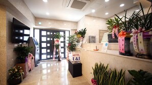 A hotel reception area with a polished marble floor, a reception desk, and various potted plants. - Hotel You&I (Incheon)