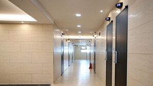 A modern hallway with numbered doors, recessed lighting, and a fire extinguisher. - Hotel You&I (Incheon)