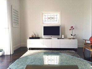 Relax in this stylish living room with a flat-screen TV, glass coffee table, and comfortable seating.