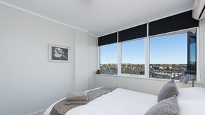 Une chambre d’hôtel avec un grand lit, une vue sur la ville et un tableau encadré au mur.