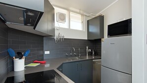Une cuisine moderne avec des meubles gris, un réfrigérateur en acier inoxydable et un four à micro-ondes noir.