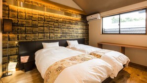 Ett hotellrum med en sänggavel med ett mönster som efterliknar tegelstenar, ett stort fönster med utsikt, ett nattduksbord och en säng med vita sängkläder.