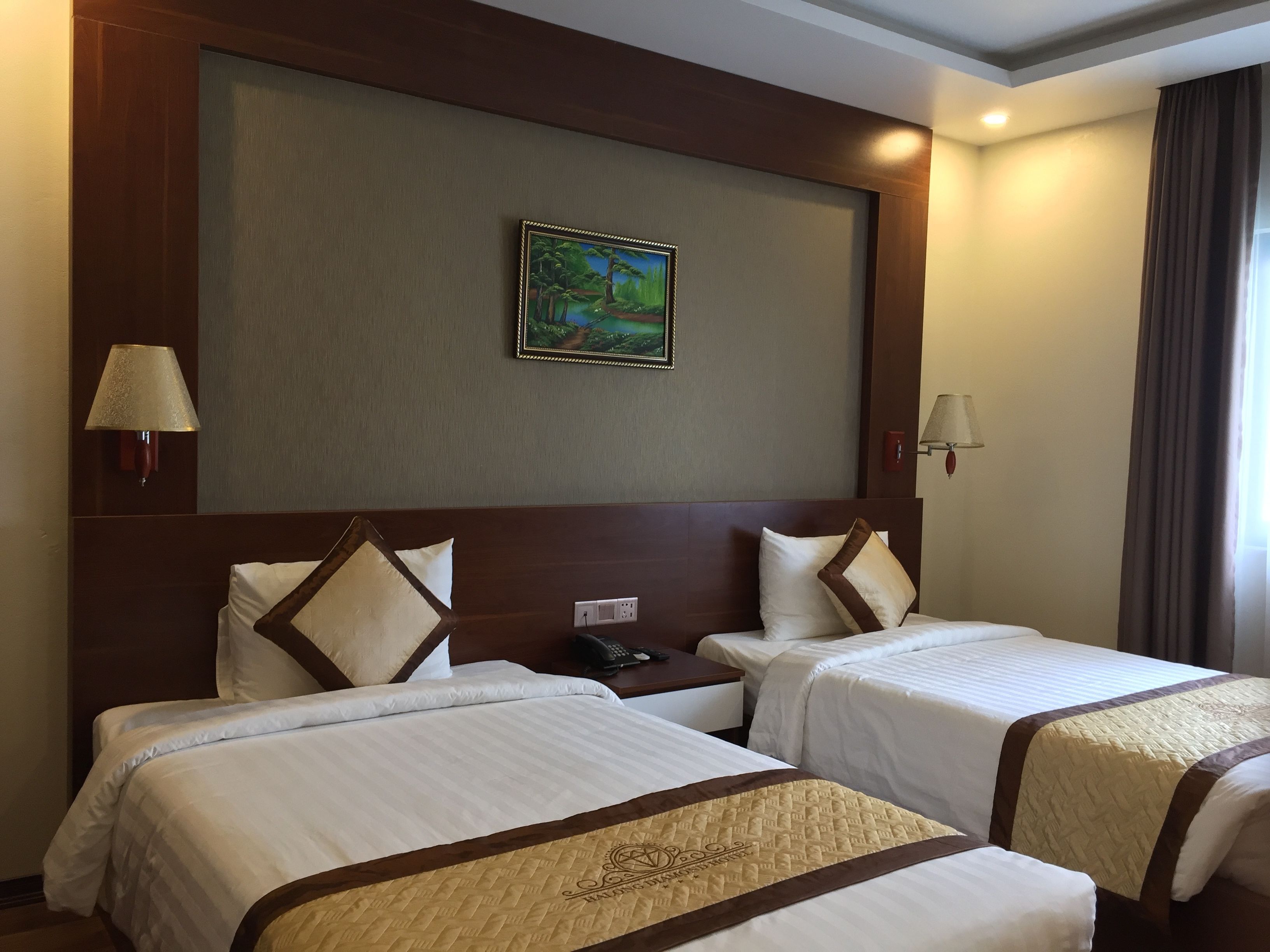 A hotel room with two beds, a painting on the wall, and two bedside lamps.