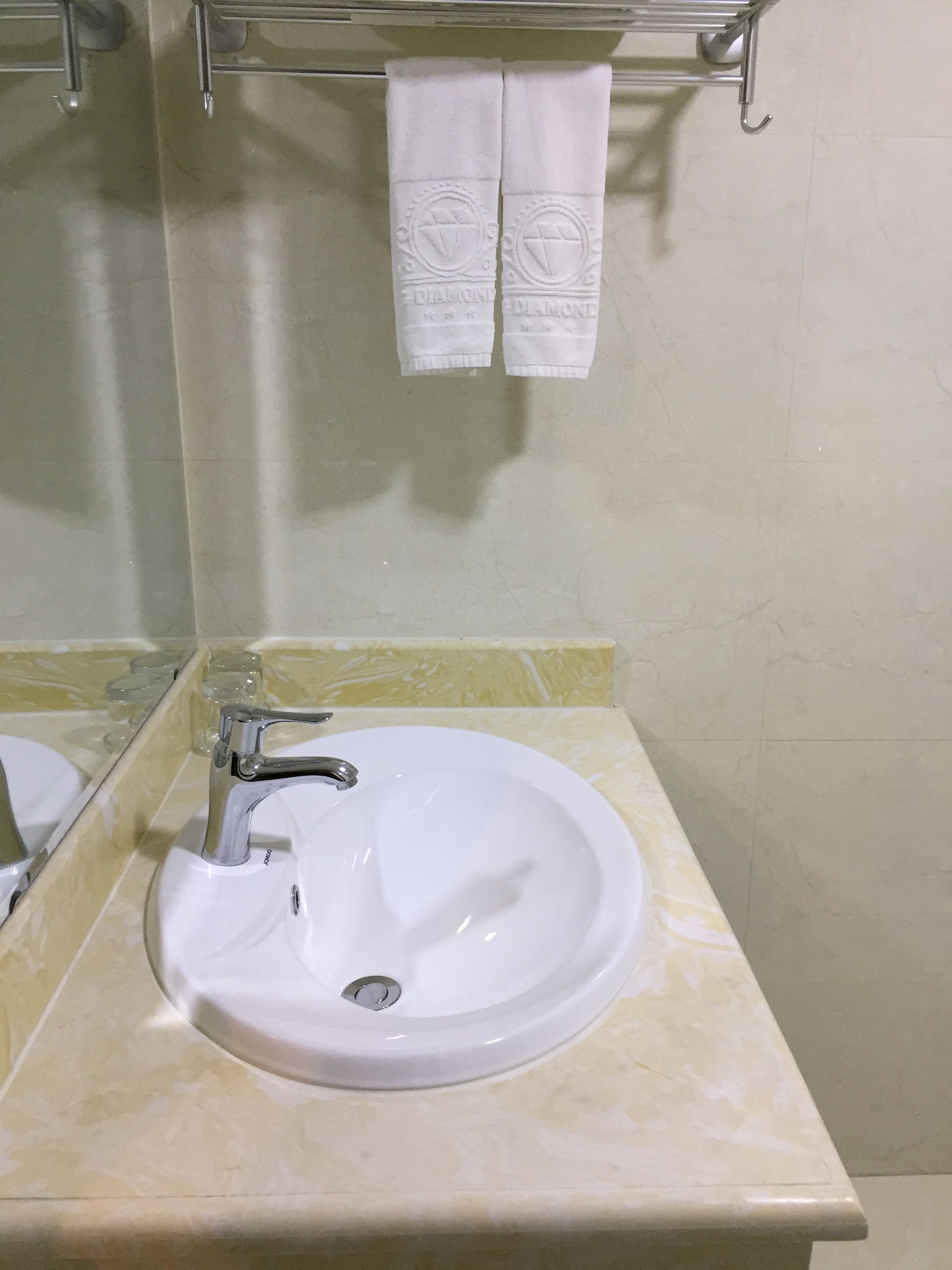 A bathroom with a white sink, chrome faucet, and a mirror. There are two white towels hanging on a rack above the sink.