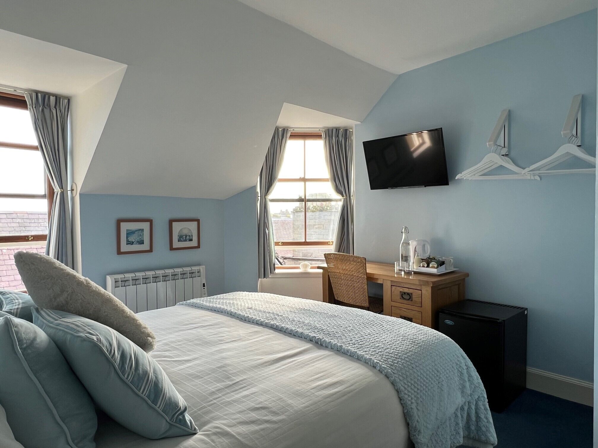A bedroom with a bed, a desk, a TV, and a radiator.
