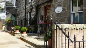 A stone building with a wooden door, a sign above the door, and a staircase leading to the entrance. - Fort Charlotte Guesthouse (Lerwick)