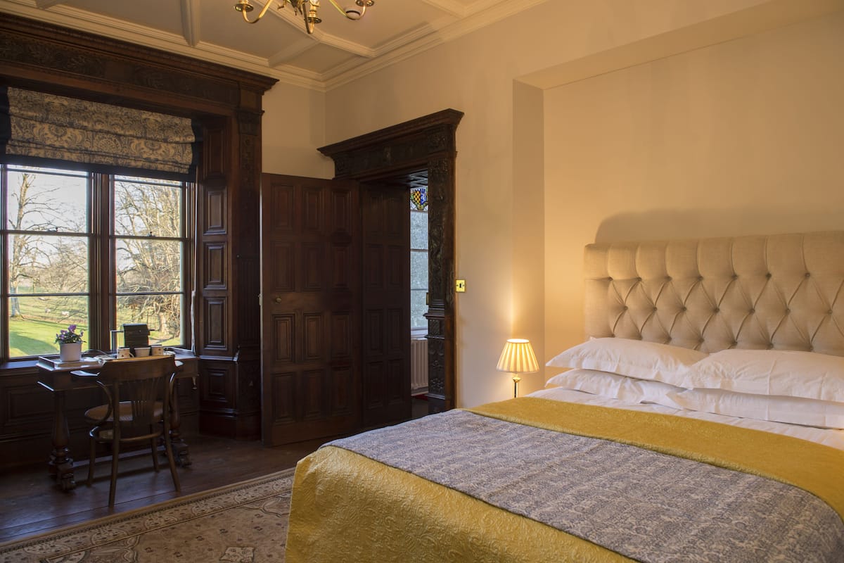 Un dormitorio con una cama grande, un escritorio con una silla y una ventana con vistas al exterior.