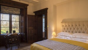 Un dormitorio con una cama grande, un escritorio con una silla y una ventana con vistas al exterior.