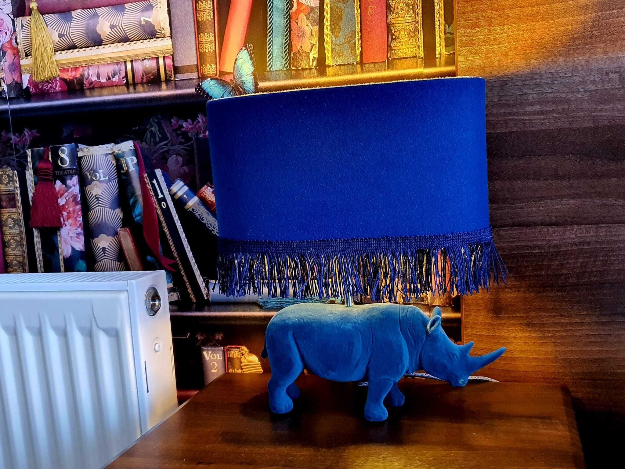 A room with a blue sofa, a decorative blue rug, and a plush blue rhinoceros toy on the floor.