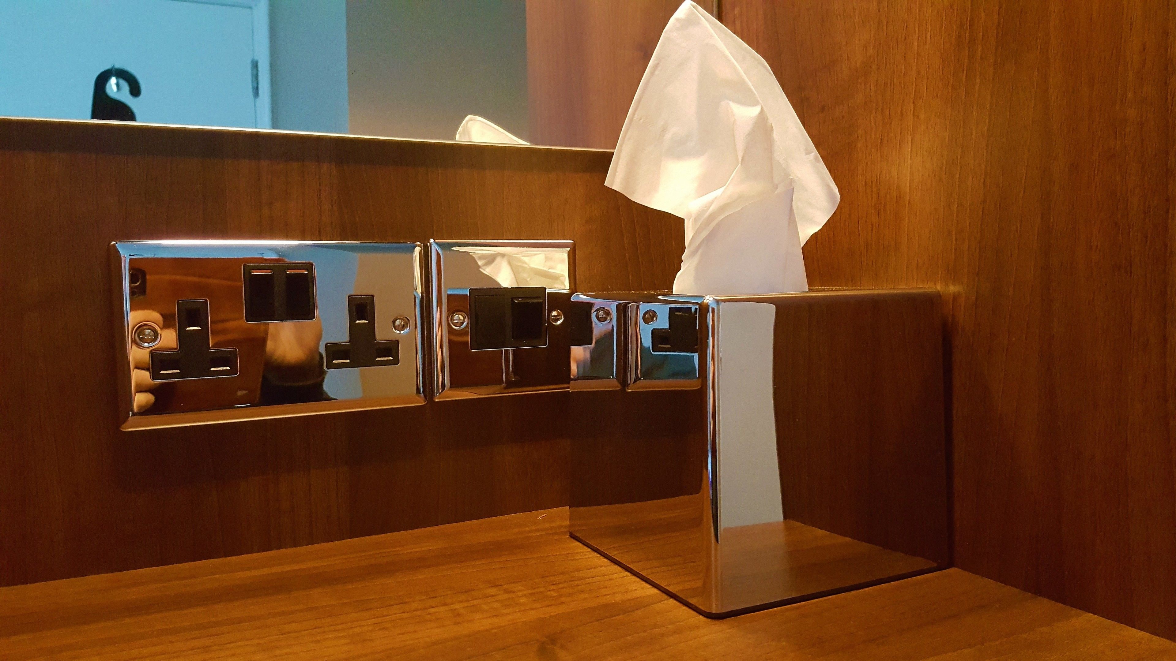 A row of three mirrored dispensers with a tissue box on the right.