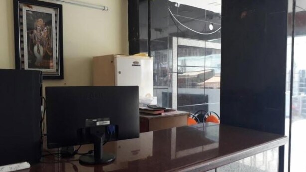A reception area with a desk, computer, and a refrigerator. - Hotel Krishna Grand Inn (Guntur)