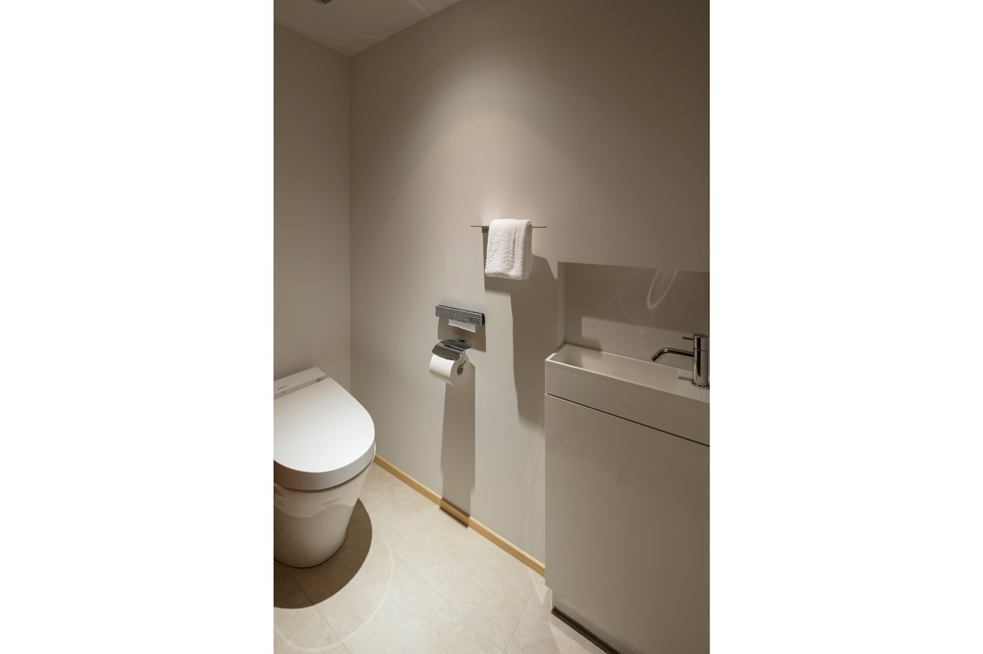 Een moderne badkamer met toilet, handdoekdispenser en wastafel.