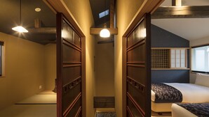 Una habitación tradicional japonesa con suelo de tatami, una cama de madera baja y puertas correderas.