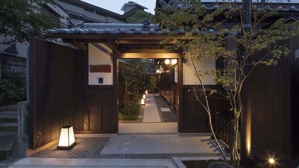 Una entrada japonesa tradicional con un farol y un sendero que conduce al interior.