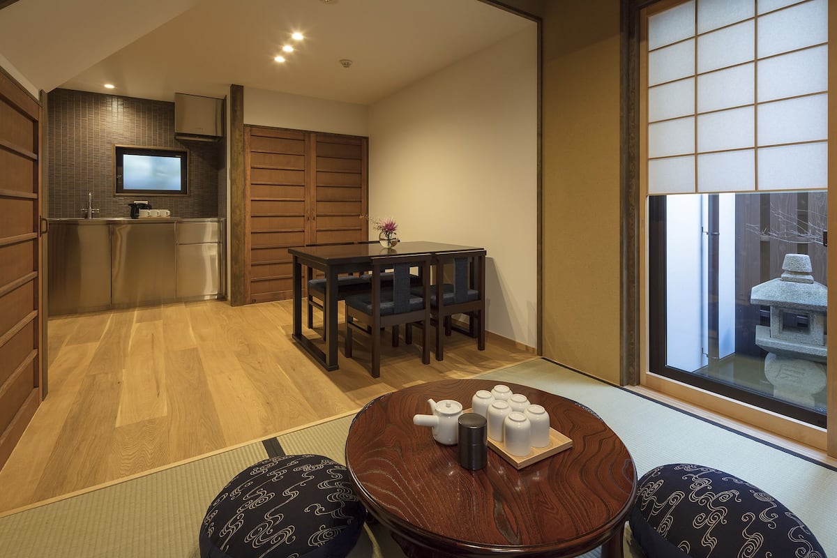 Une pièce de style japonais traditionnel, avec un sol recouvert de tatamis, une table basse en tatami accompagnée d’un service à thé, une télévision et des portes coulissantes.