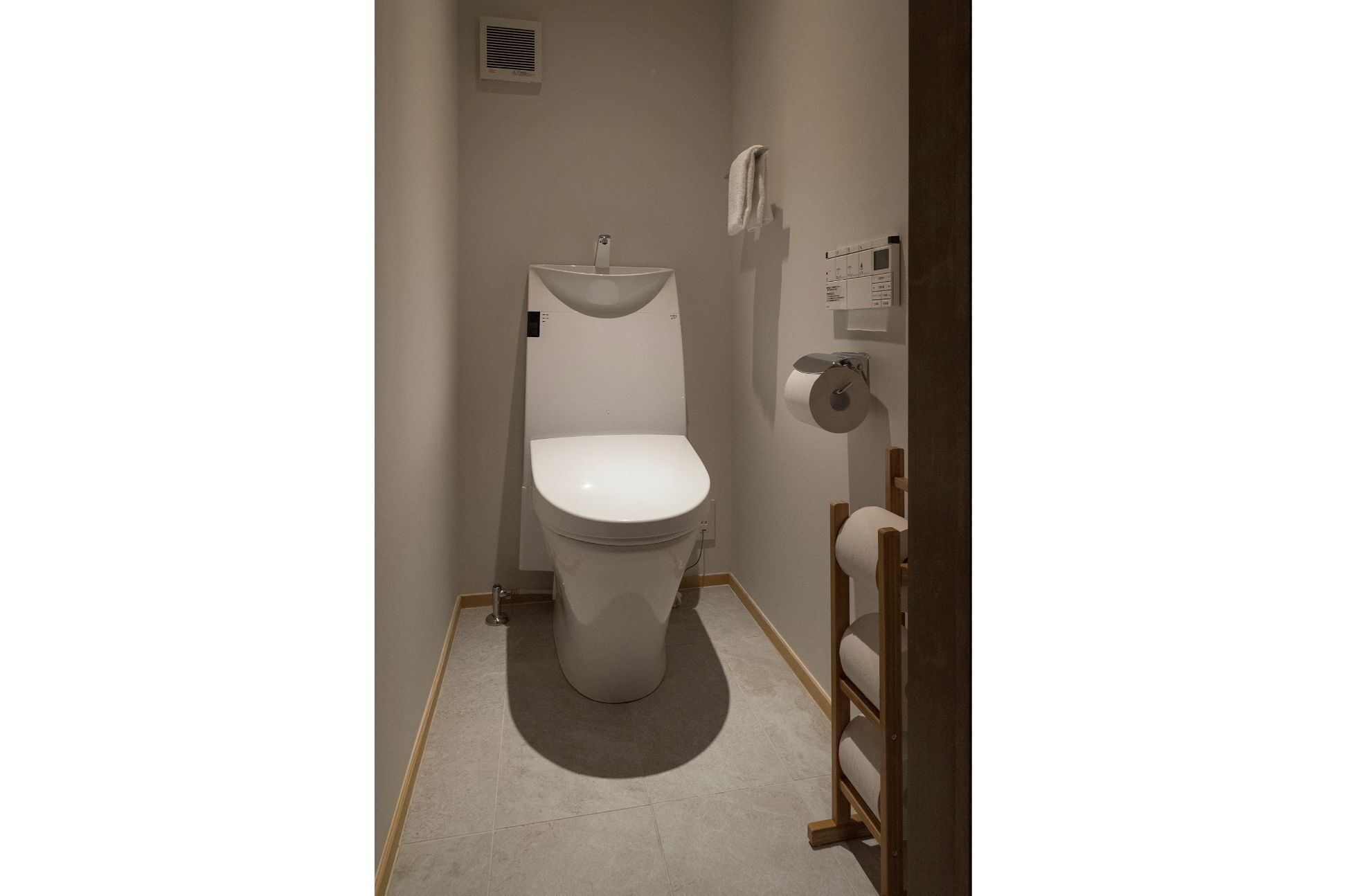 A compact bathroom with a white toilet, a towel rack, and a toilet paper holder.