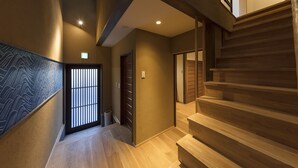 Un interior moderno con una escalera de madera, una pared estampada y una puerta con reja de metal.