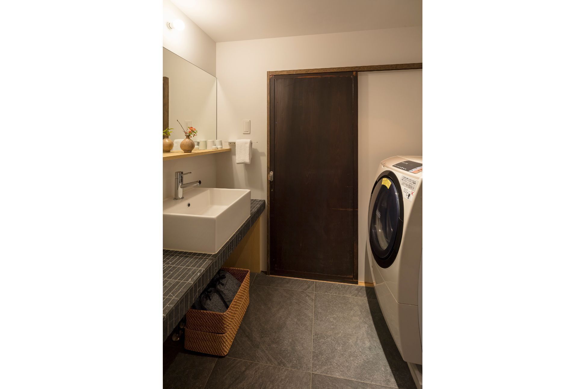 A compact bathroom with a sink, mirror, and a washing machine.