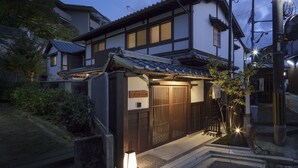Una casa tradicional japonesa con un portón de madera, un pequeño jardín y un farol.