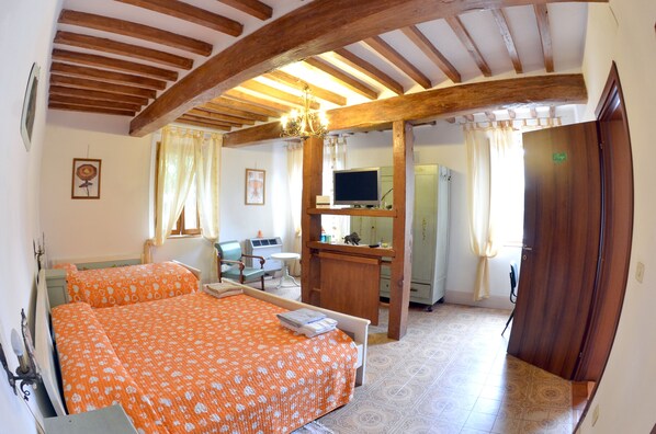 A bedroom with two beds, a desk with a computer, a TV, and a bathroom visible through an open door. - B&B Reboglio (Rolo)