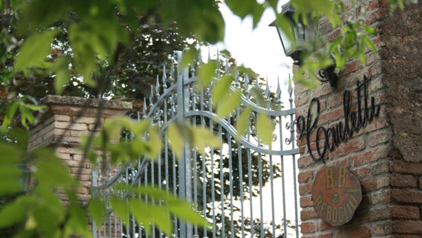 Un portail en fer forgé, un mur en briques et une enseigne indiquant « B&B Reboglio ».