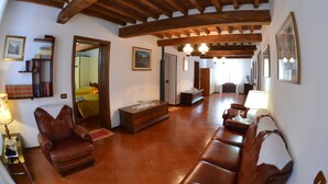 A spacious living room with a wooden ceiling, leather sofas, a coffee table, and a bookshelf. - B&B Reboglio (Rolo)