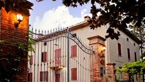 A gated property with a brick entrance, a stone pillar, and a light fixture on the wall. - B&B Reboglio (Rolo)