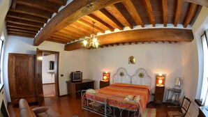 A bedroom with a bed, a desk, a chair, a sofa, and a wooden ceiling. - B&B Reboglio (Rolo)