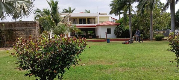 Un quartier résidentiel avec une maison, une pelouse et une personne qui tond la pelouse.
