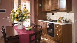 A kitchen with wooden cabinets, a gas stove, and a dining table with chairs. - Agriturismo Le Dolci Colline (Valfabbrica)