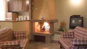 A living room with a fireplace, two plaid sofas, a television, and wooden cabinets. - Agriturismo Le Dolci Colline (Valfabbrica)