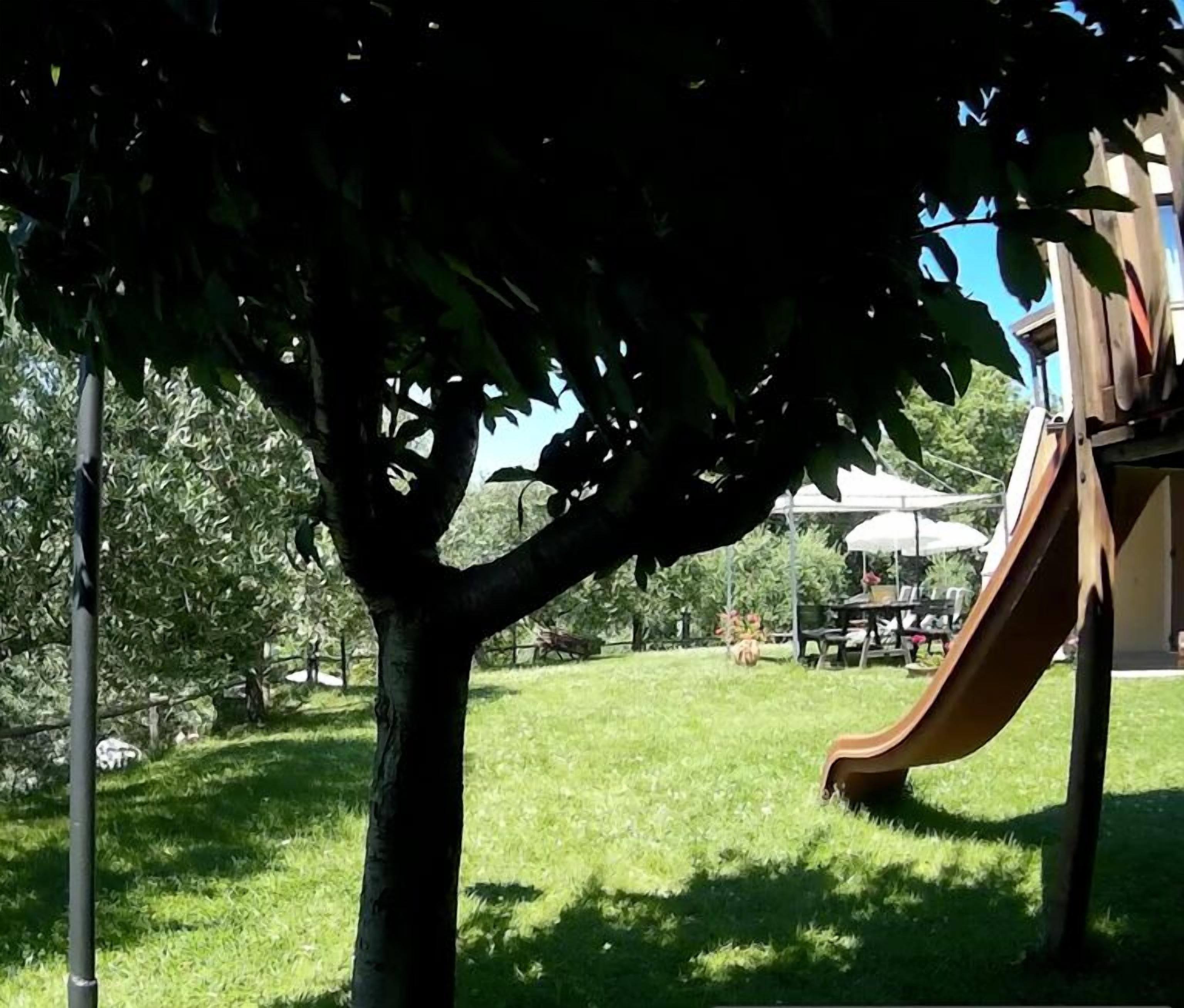 Une aire de jeux avec un toboggan et une table de pique-nique, située dans un espace verdoyant.