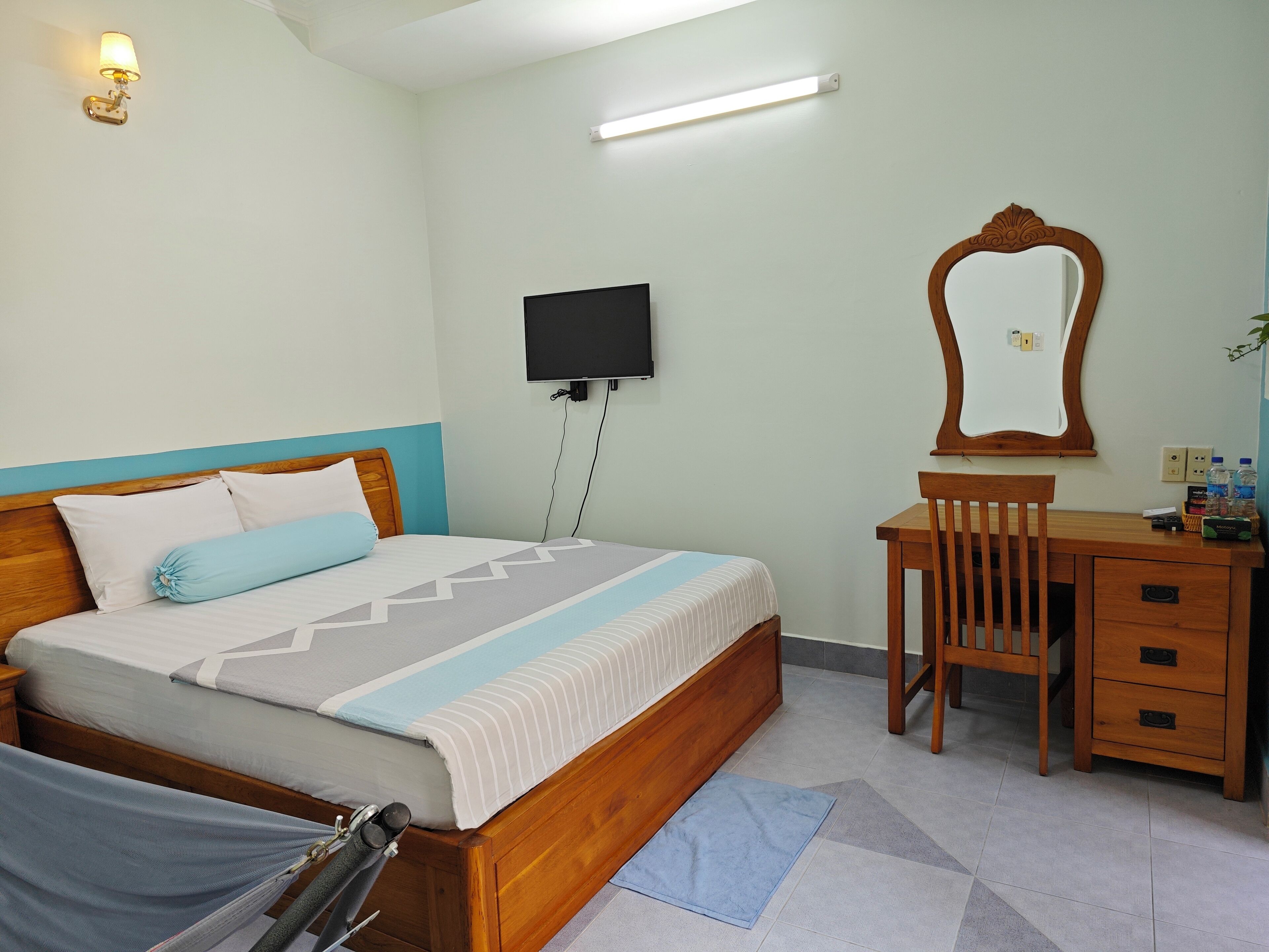 Une chambre à coucher comprenant un lit, un bureau, une chaise, une télévision et un miroir.