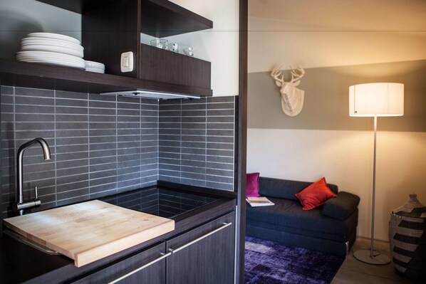 A modern kitchen with a built-in sink, dark cabinetry, and a wooden cutting board. - Camping Village Rocchette (Castiglione della Pescaia)