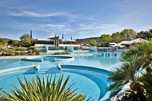 A modern resort with a large infinity pool, a poolside bar, and a mountain backdrop. - Camping Village Rocchette (Castiglione della Pescaia)