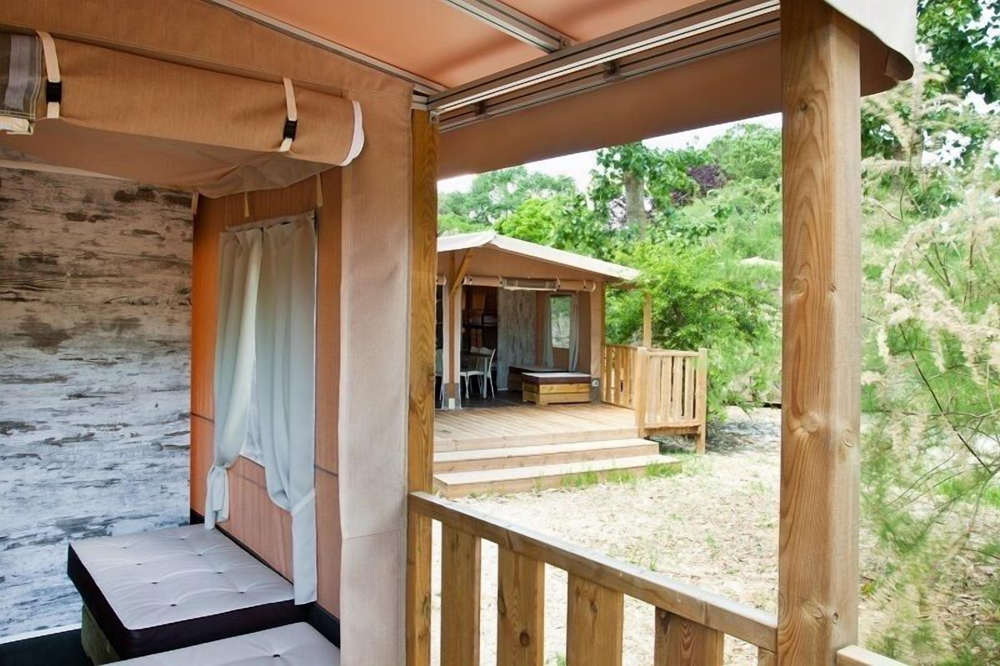 A wooden deck with a covered seating area, a small table, and a bench.